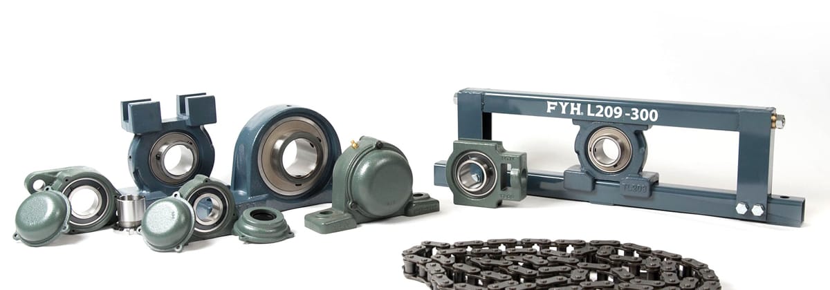 さまざまなサイズや形状のベアリングユニット、ピローブロック、および金属製のローラーチェーンが白背景に並べられた、産業機械用部品の集合写真。