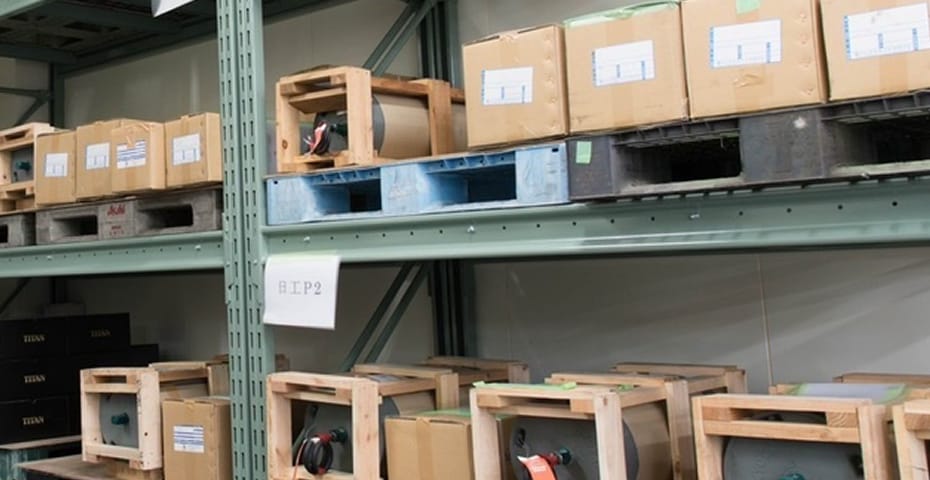 倉庫の棚に整然と並べられた、木枠で梱包された大型機械部品